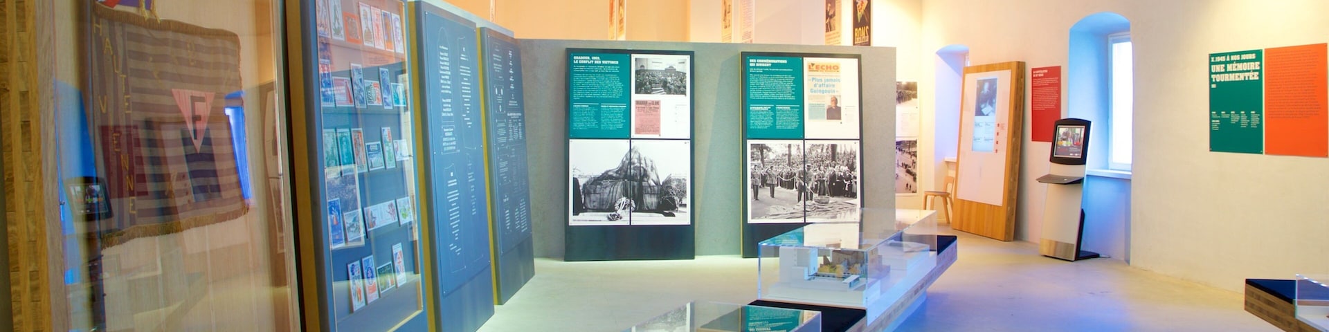 An indoor exhibition with glass display cases, informational posters, and a wooden bench.