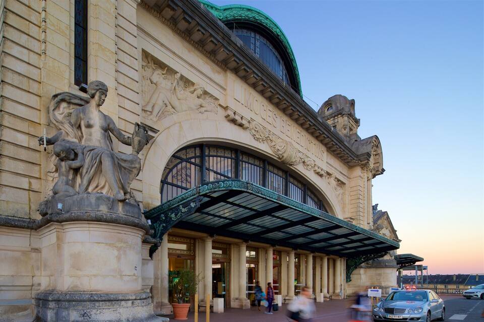 A historic building with classical architecture, including a large statue and ornate columns.