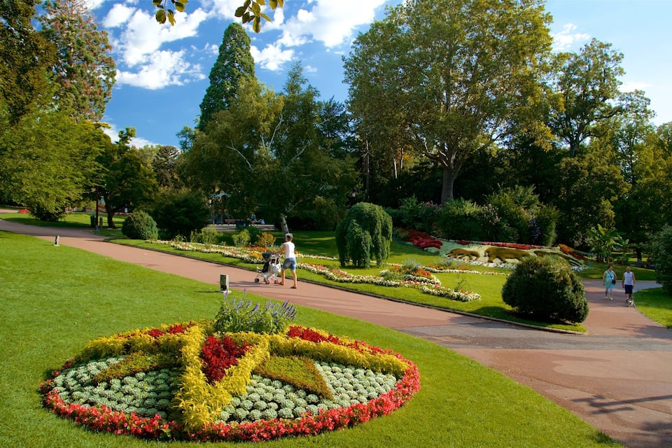 Un parc comprenant un grand parterre floral en forme de symbole de la paix, des sentiers pédestres et différentes espèces d’arbres.