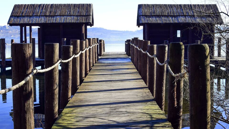 A wooden pier leading to two thatched-roof structures.