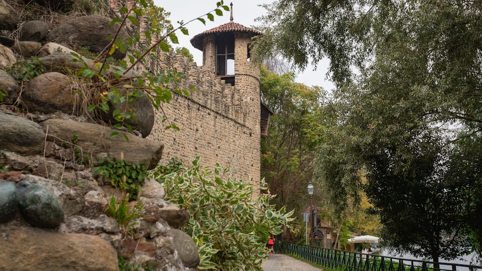 Una torre in pietra con tetto in tegole, circondata da rocce e vegetazione.