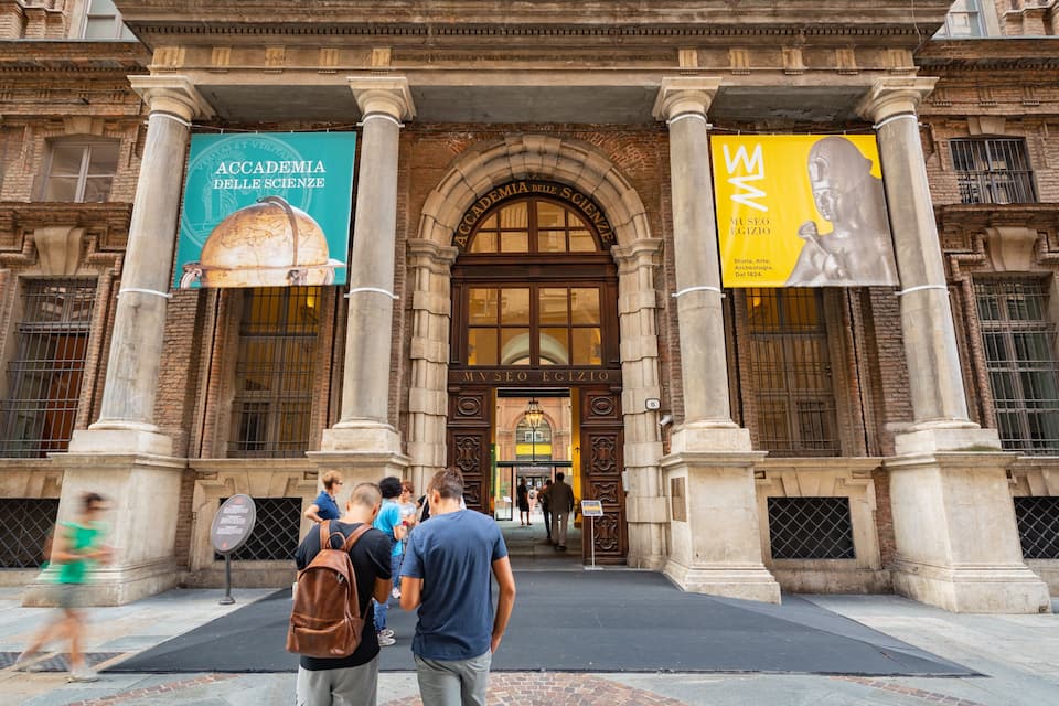 The entrance to the Accademia delle Scienze with large banners and a statue.