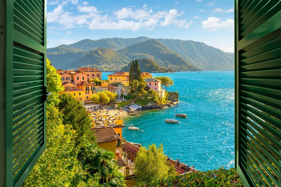 A coastal town with colorful buildings, boats on the water, and mountains in the background.