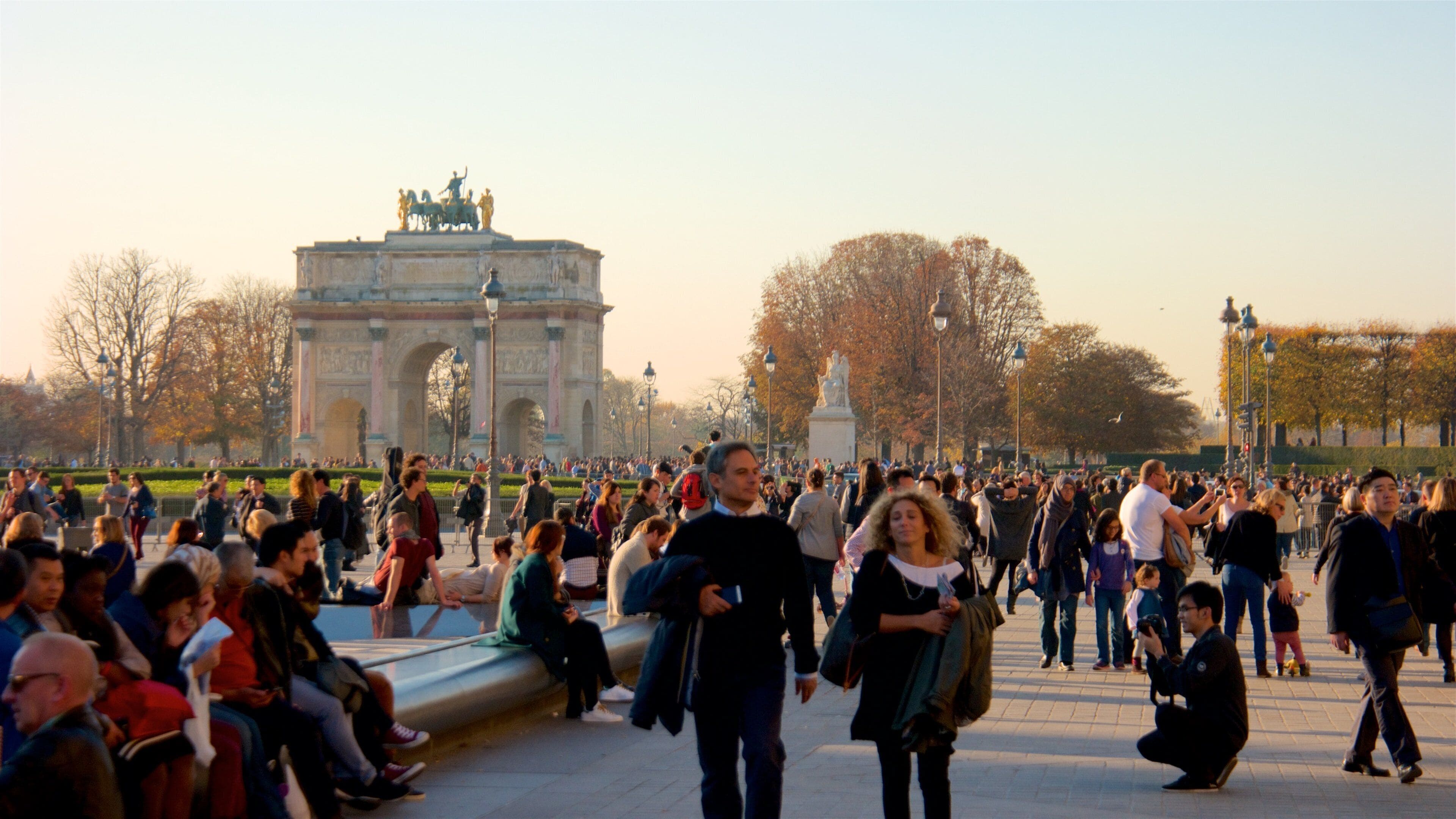 Arc de Triomphe du Carrousel which includes heritage elements and a sunset as well as a large group of people