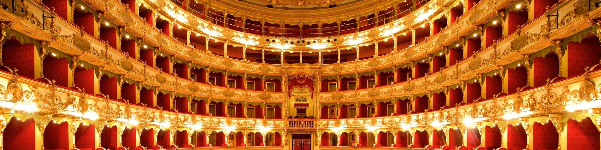 An ornate theater with red velvet seats and a grand, decorated ceiling.