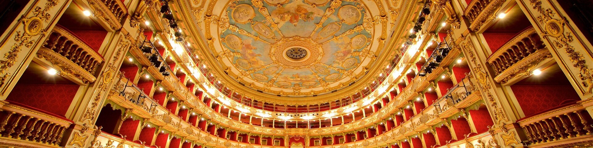 Un teatro ornamentado con un techo circular imponente y asientos de terciopelo rojo.