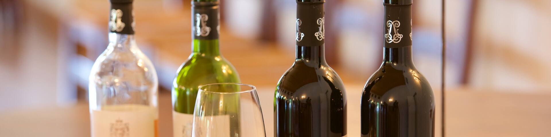 Quatre bouteilles de vin et un verre à vin sur une table en bois.