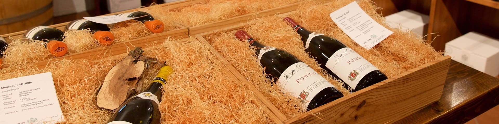 A wine display with bottles in wooden crates, surrounded by shelves of wine bottles.