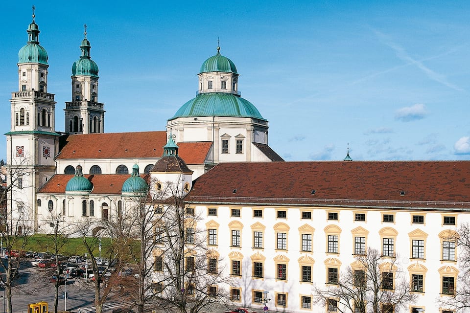 A historic building with green domes and a clock tower.
