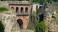 A historic stone bridge with arches, a stone wall, and a pathway.
