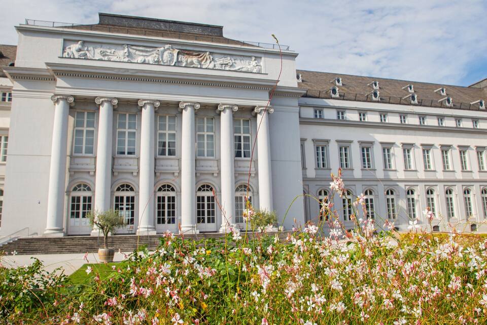 A grand classical building with columns and a statue on the roof.