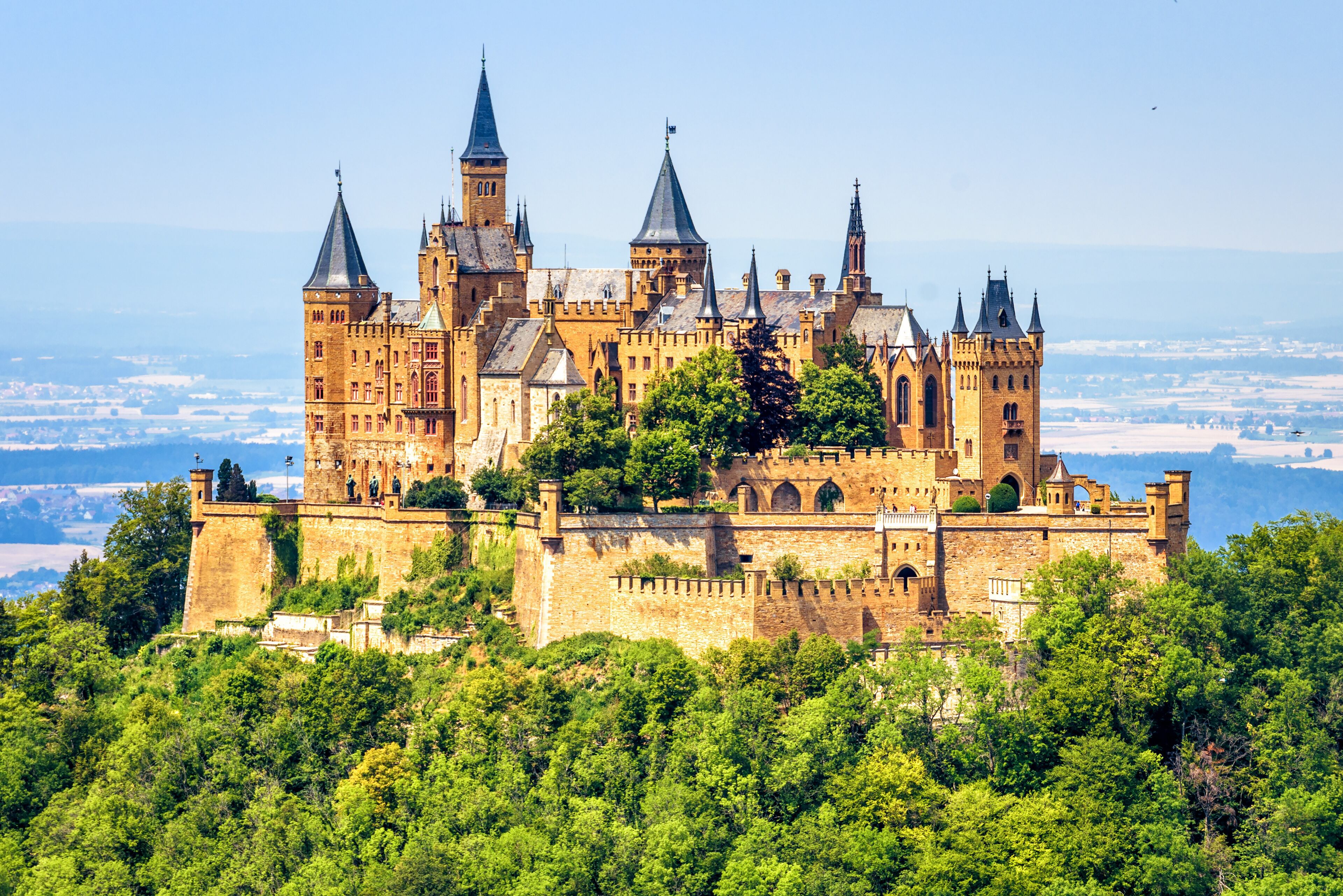 Hohenzollern Castle on mountain top close-up, Germany. Fairytale castle is famous landmark near Stuttgart. Scenic view of mount Burg Hohenzollern in forest.