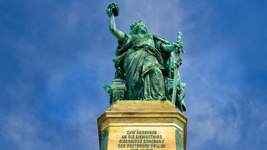 A statue of a woman holding a torch and a tablet, with a clear blue sky in the background.