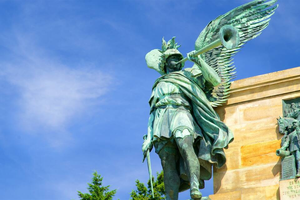 Eine Statue eines Engels mit Flügeln und einer Trompete, die auf einem Gebäude befestigt ist.