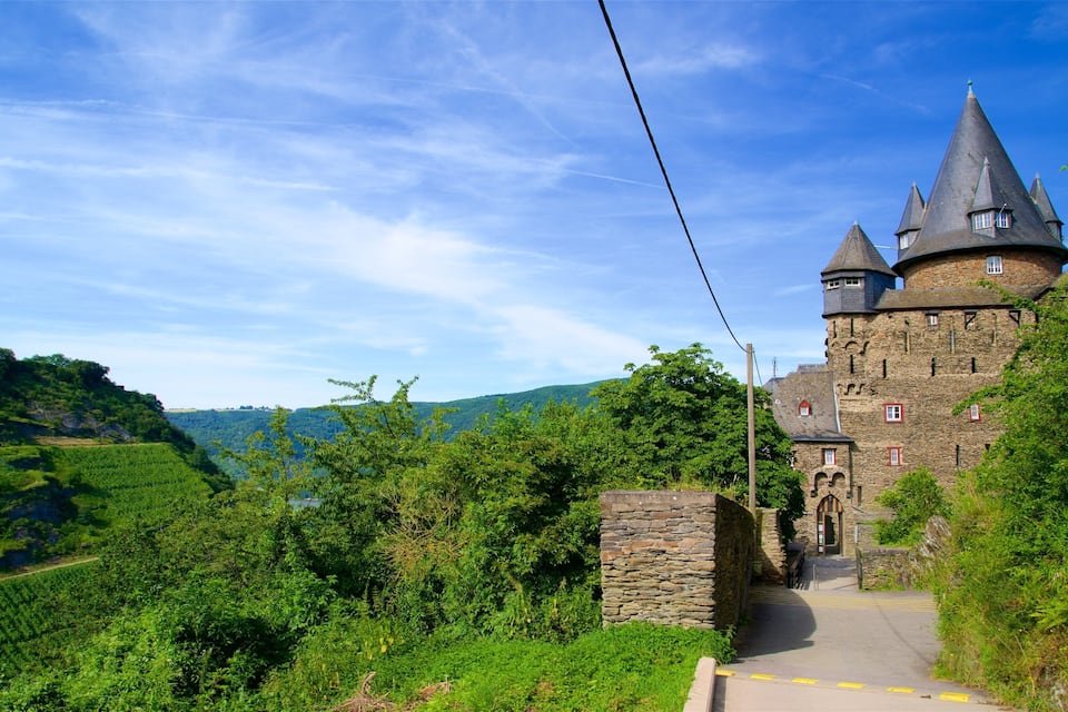 Un château médiéval doté d’une tour, entouré de collines verdoyantes et surplombant un ciel dégagé.