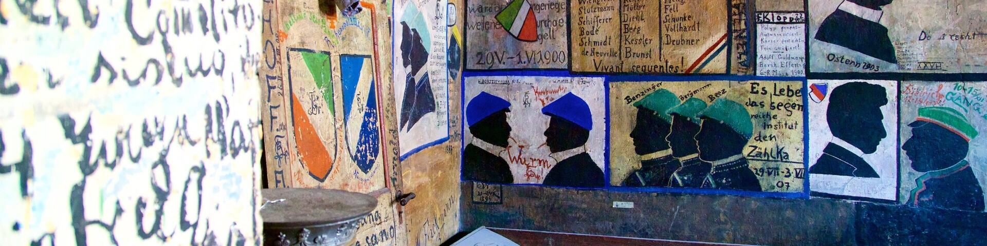 Una habitación con paredes cubiertas de carteles históricos y grafitis.