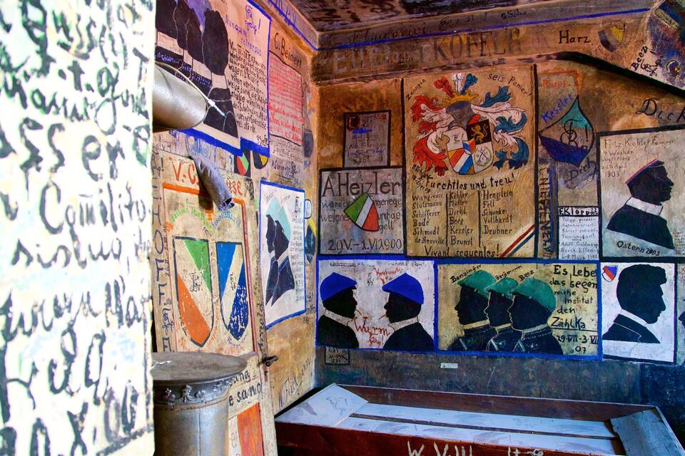 Ein Zimmer mit Wänden, die mit historischen Postern und Graffiti bedeckt sind.