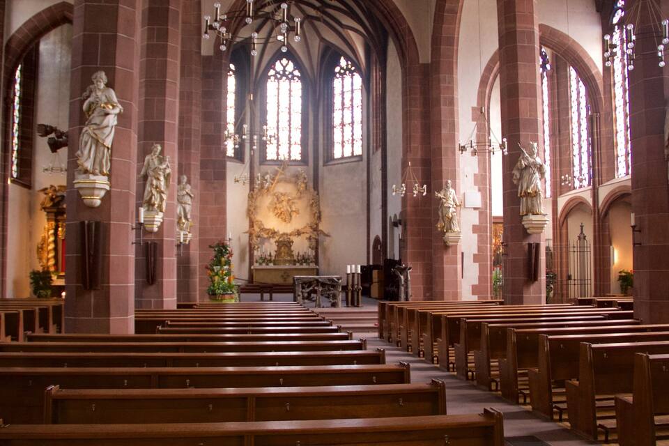 Interior d'església amb pews de fusta, finestres de vitralls i estàtues.