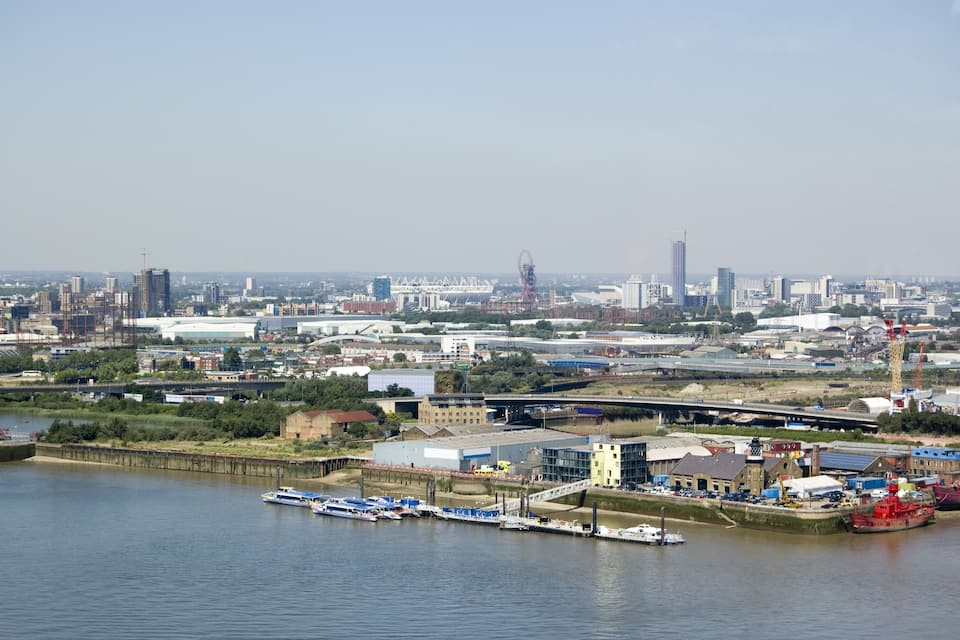 A river with boats, a bridge, and a city skyline with buildings and a Ferris wheel.