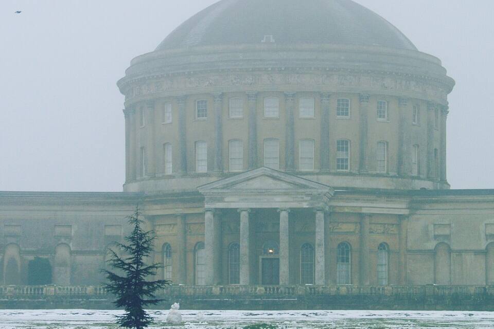 A large, classical building with a dome and columns, surrounded by a snowy landscape.