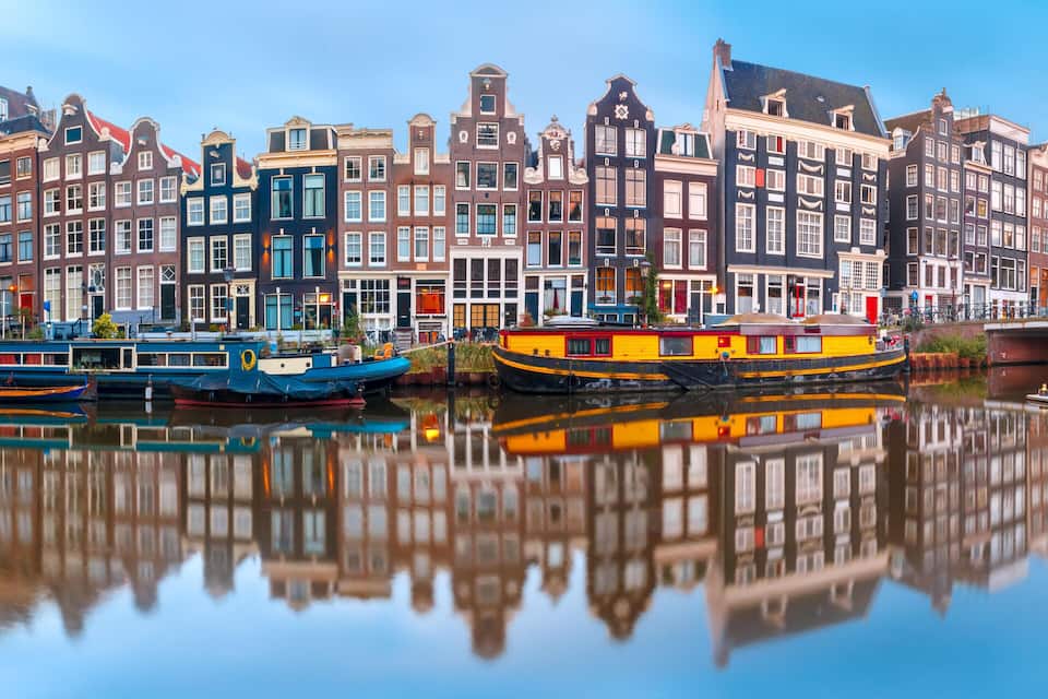A canal with boats and colorful buildings reflecting on the water.