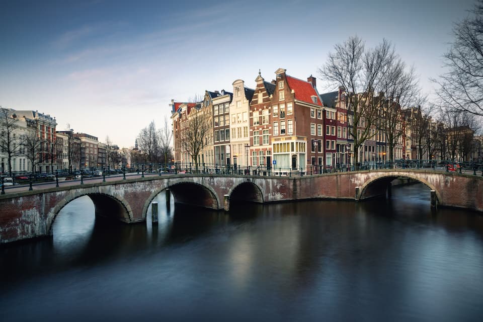 Un canal bordé de bâtiments historiques et traversé par un pont de pierre.