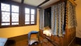 A traditional wooden bed with a canopy, a small stool, and a window with a geometric pattern.