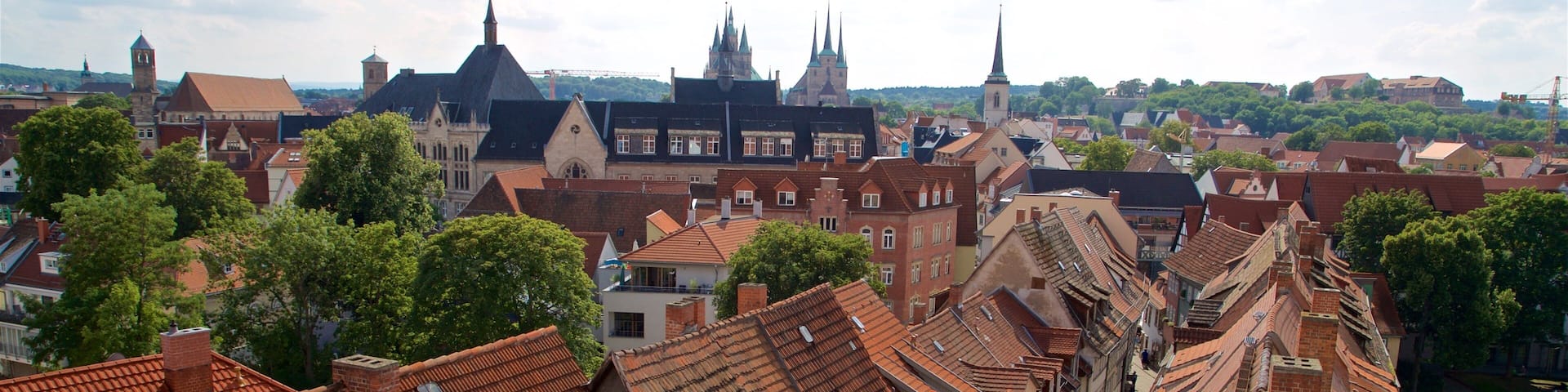 A cityscape with red-tiled roofs, historic buildings, and a prominent church tower.