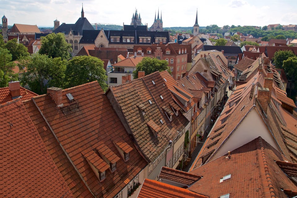 A cityscape with red-tiled roofs, historic buildings, and a prominent church tower.