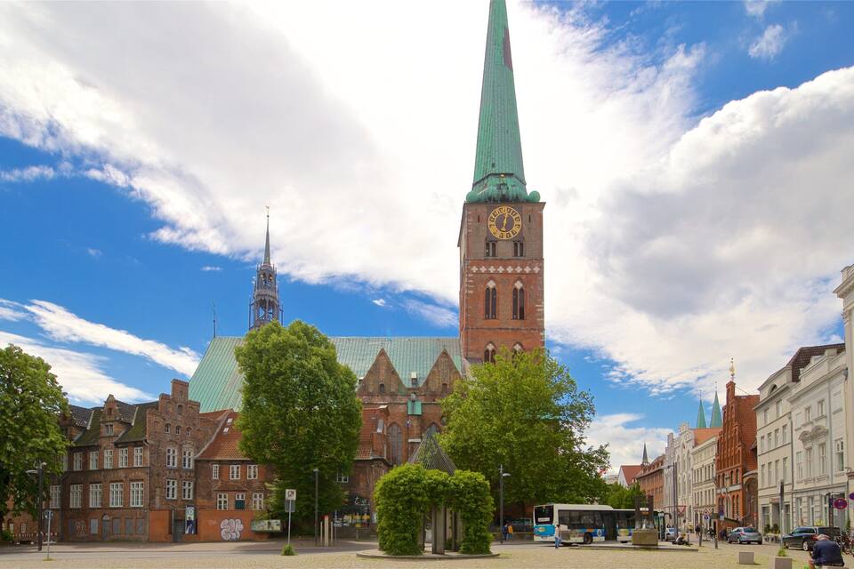Una iglesia histórica con una aguja alta, una torre del reloj y un autobús moderno al frente.