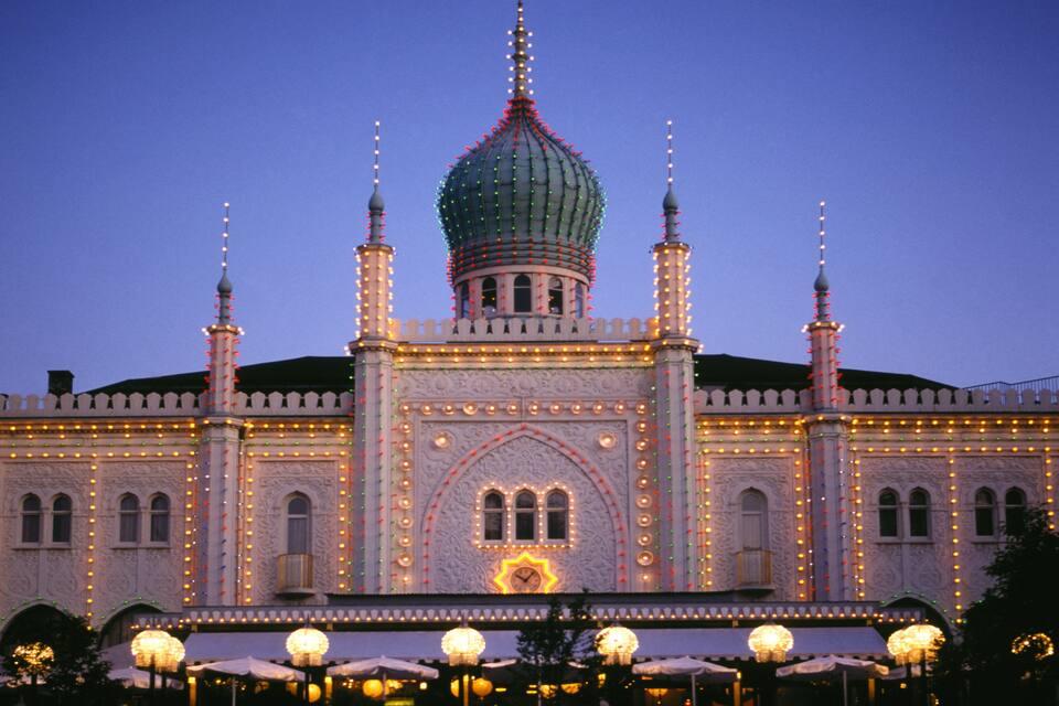 A grand building with a large dome and multiple minarets, adorned with lights.