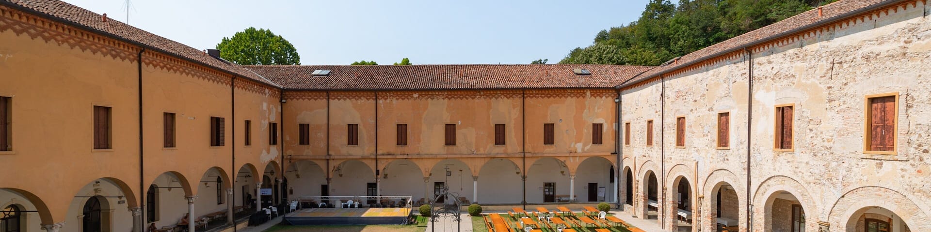 A courtyard with a central fountain, surrounded by buildings with arched windows and a tiled roof.