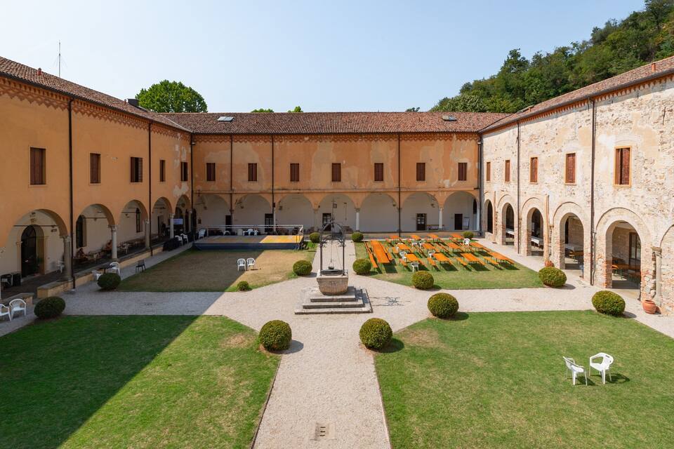 A courtyard with a central fountain, surrounded by buildings with arched windows and a tiled roof.