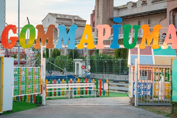 Une porte d’entrée colorée, sur laquelle on peut lire le texte « GOMMAPUNGA », et un personnage tenant une pancarte.