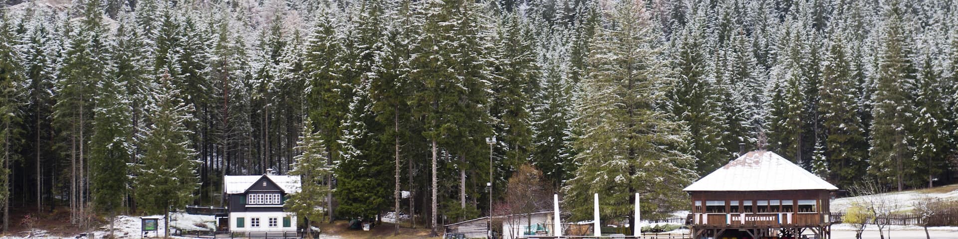 Snow-covered forest and houses reflected in Lake Toblach, Lago di Dobbiaco, Toblach, Val Pusteria, Alto Adige, Trentino-Alto Adige, Italy