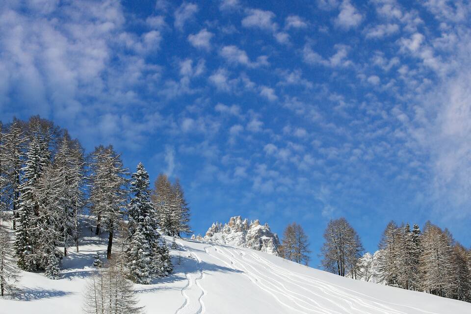 Un paysage de montagne enneigé, avec un ciel bleu dégagé et une piste de ski.