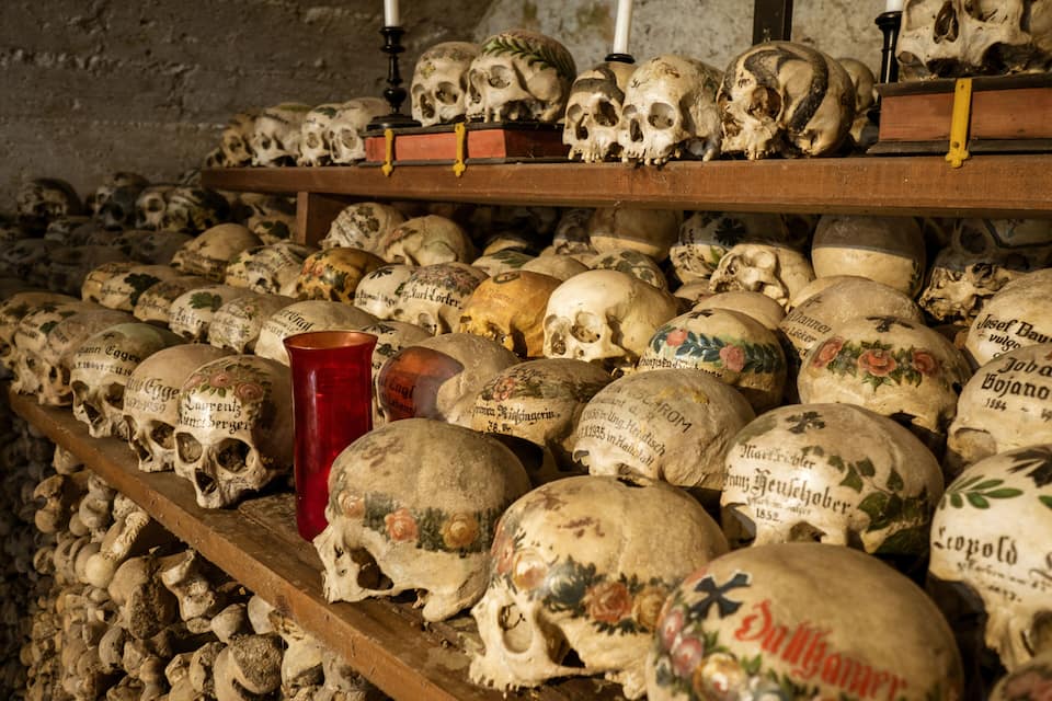 A collection of skulls with inscriptions, arranged on shelves in a dimly lit room.