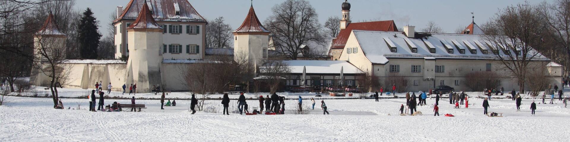 Blutenburg Castle showing snow and a small town or village as well as a small group of people