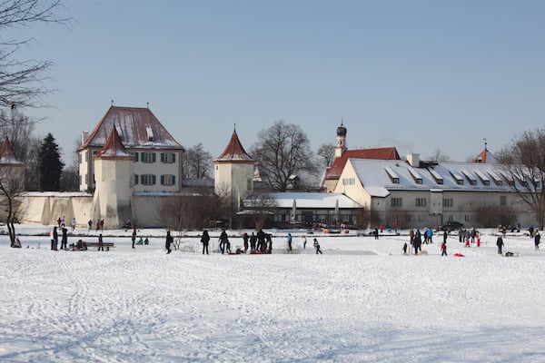 Blutenburg Castle showing snow and a small town or village as well as a small group of people