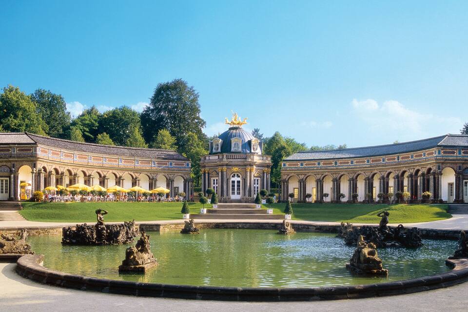 Un palacio imponente con una fuente central y jardines simétricos.