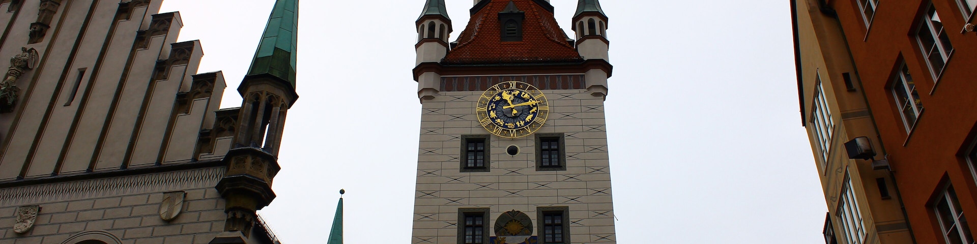 A historic tower with a clock, pointed spires, and a crest.