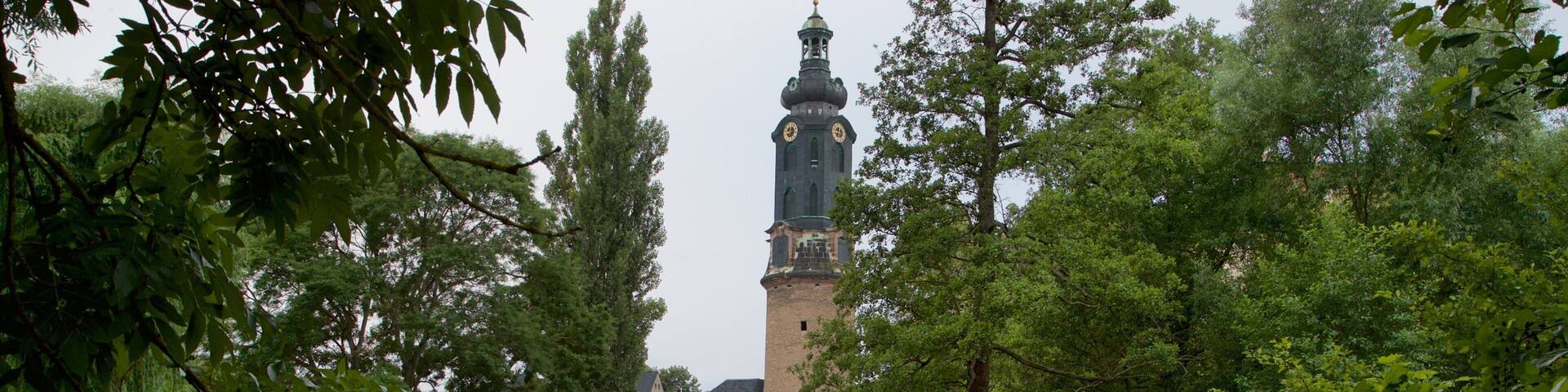 A park with a tower, trees, and a pond.