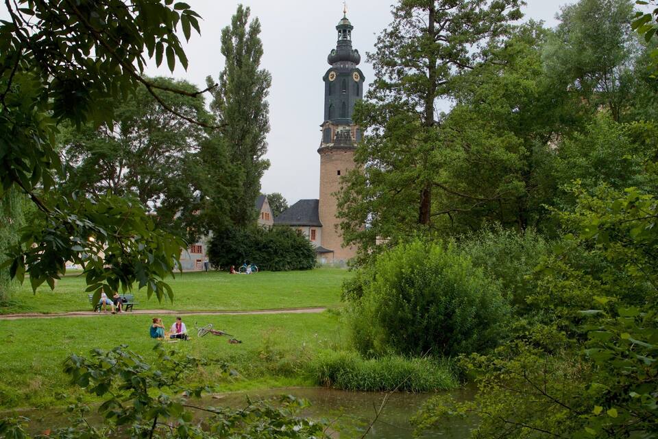 Ein Park mit einem Turm, Bäumen und einem Teich.