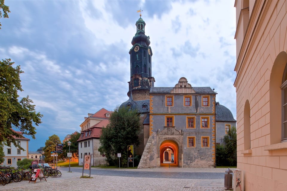 A historic building with a clock tower, cobblestone street, and bicycles parked in front.
