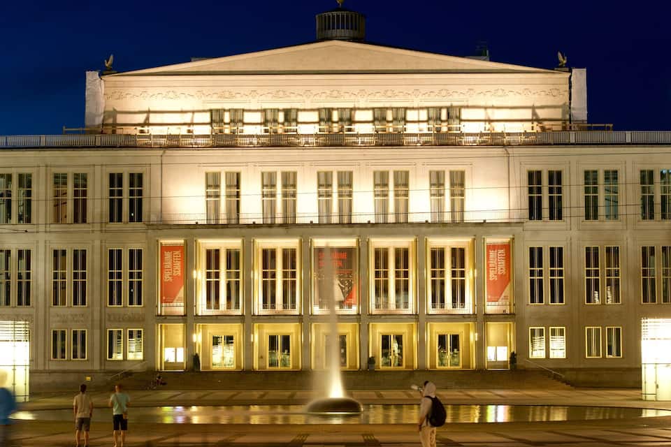 A large, illuminated building with a central fountain and banners.