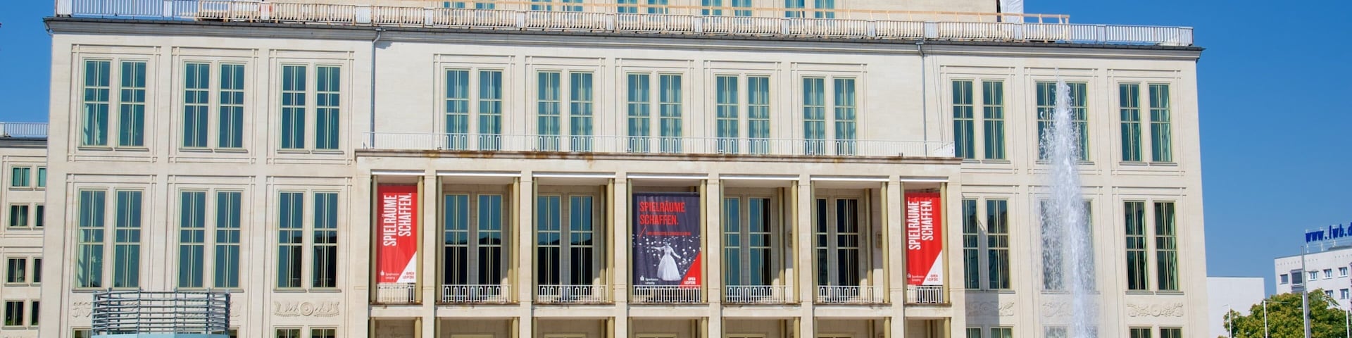 Un gran edificio clásico con una fuente en primer plano.