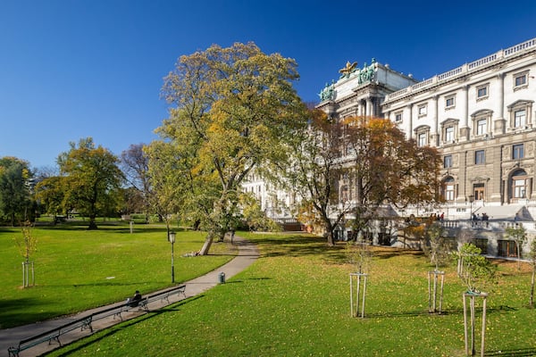 Ein Park mit einem Weg, Bänken und Bäumen mit Herbstlaub.