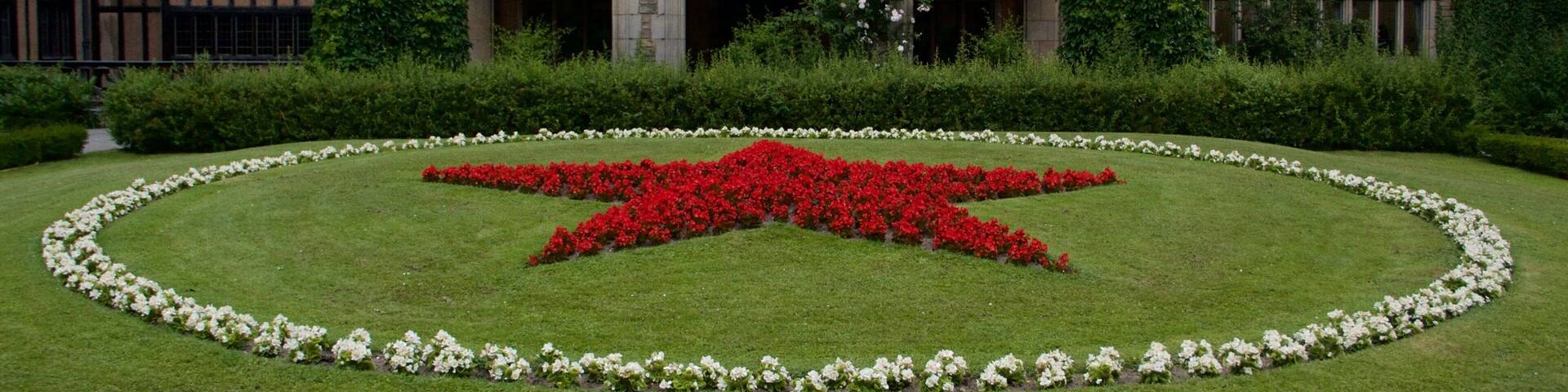 Un bâtiment historique avec un parterre floral en forme d’étoile devant.