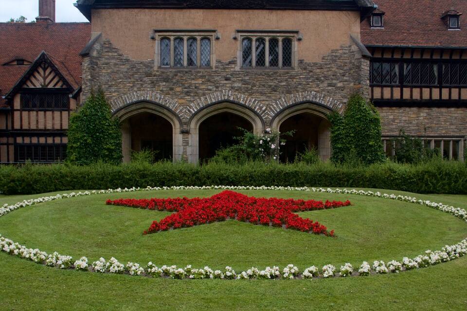 Um edifício histórico com um canteiro de flores em formato de estrela na frente.