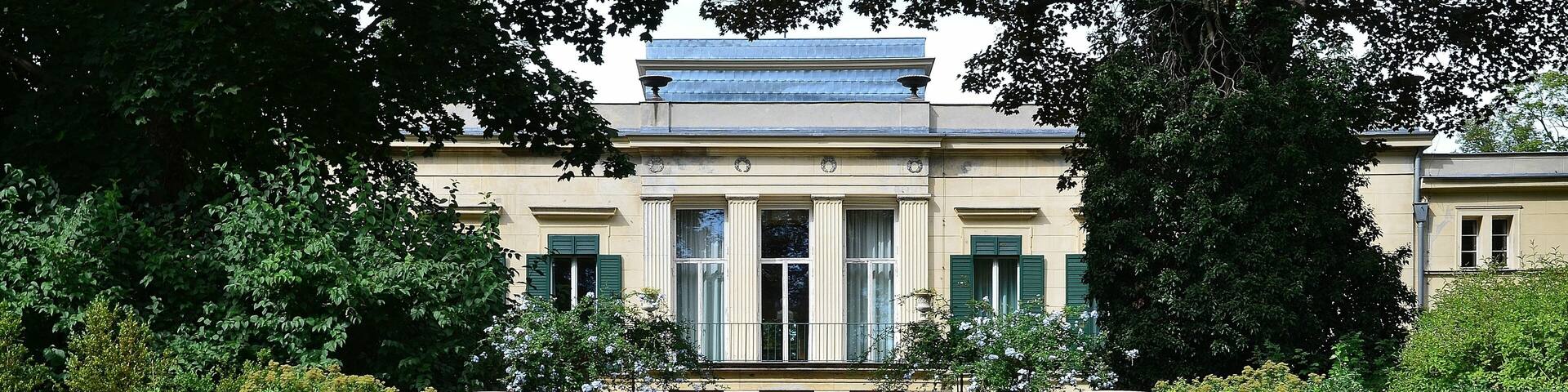 A classical building with columns, a reflecting pool, and a stone balustrade.